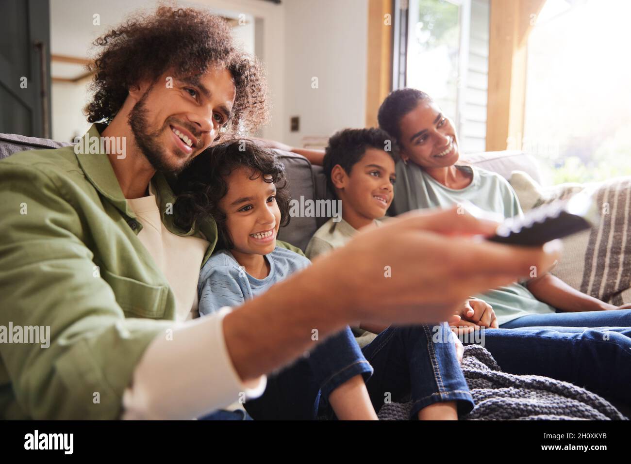 Family watching TV with father using remote Stock Photo