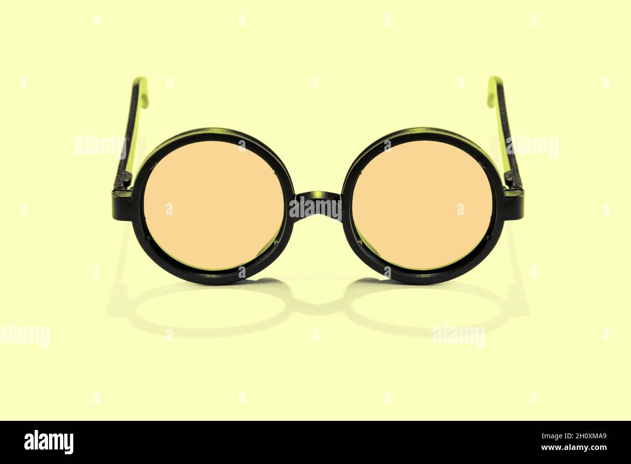 Pair of vintage reading spectacles with round frames isolated on yellow with shadow Stock Photo