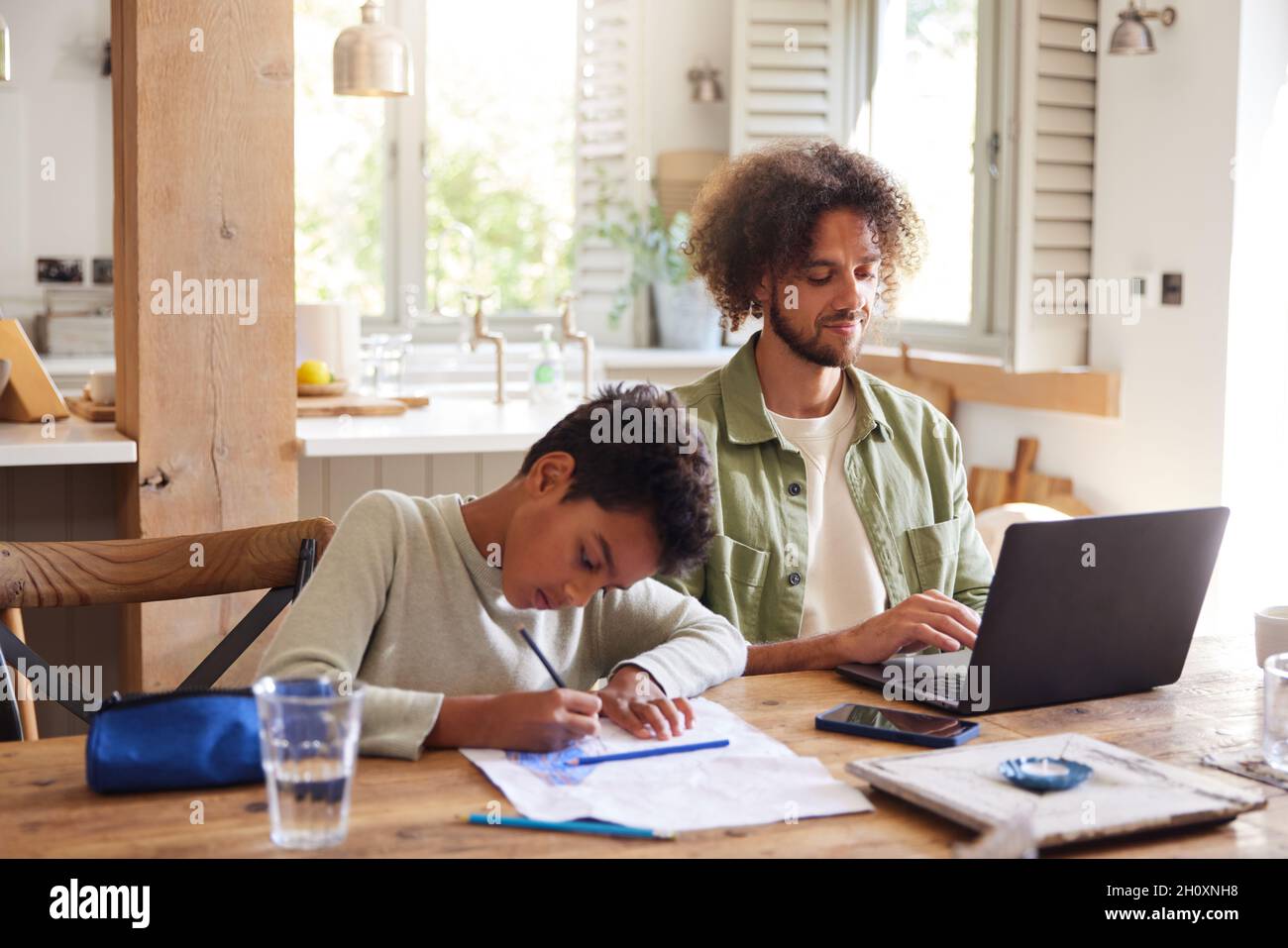 Father using laptop with son drawing at home Stock Photo