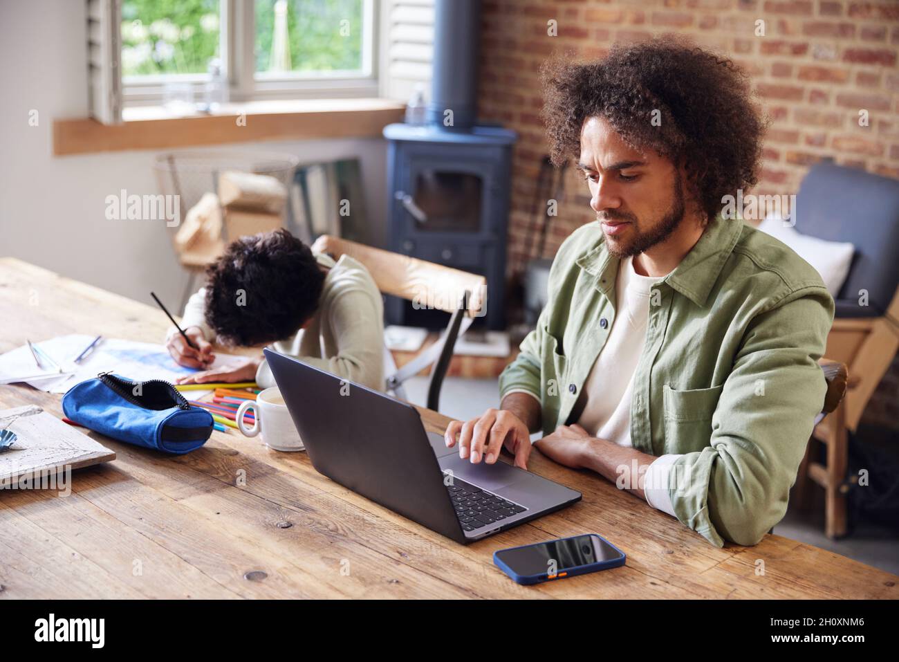Father using laptop with son drawing at home Stock Photo