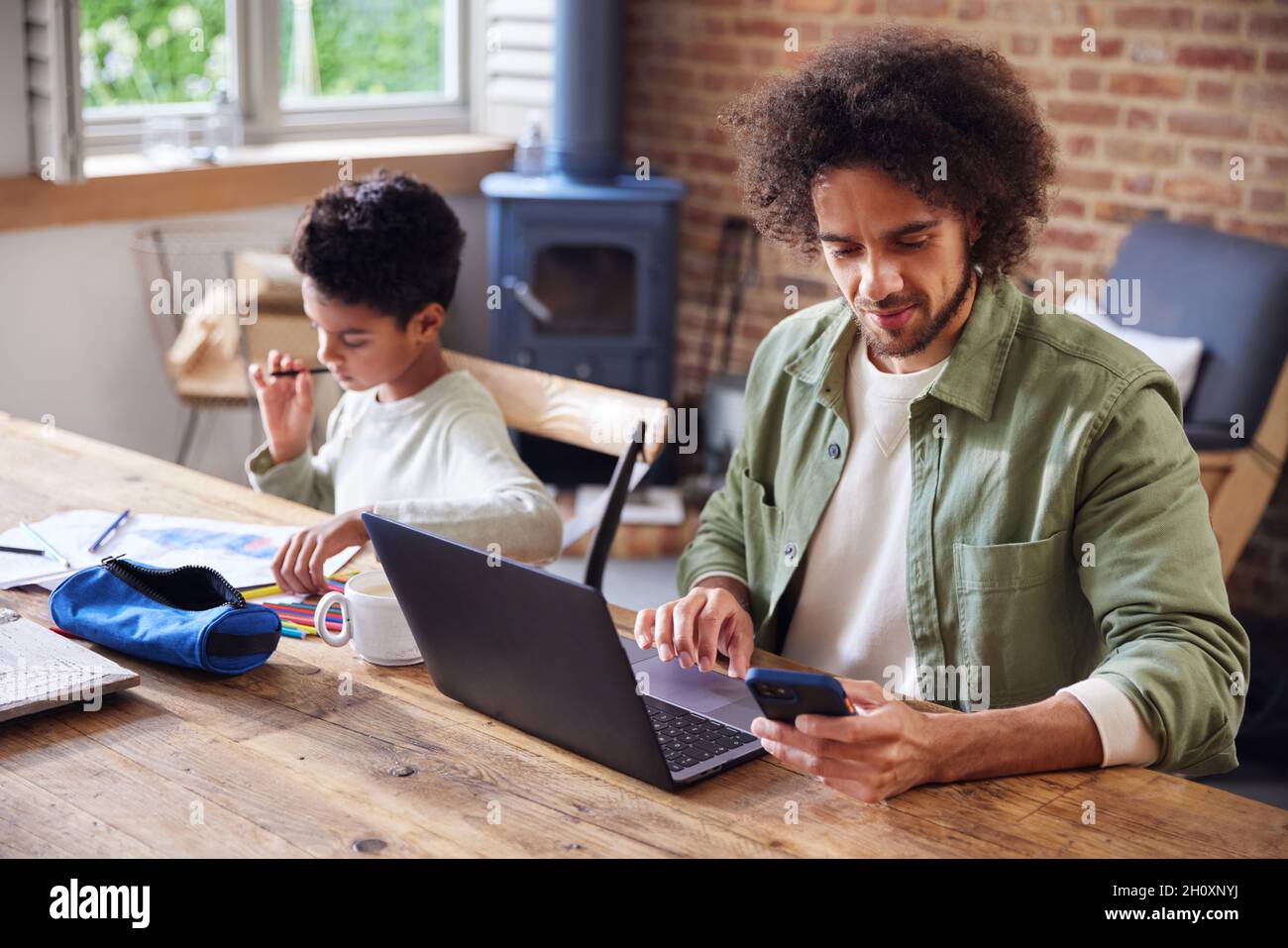 Father using laptop with son doing homework Stock Photo