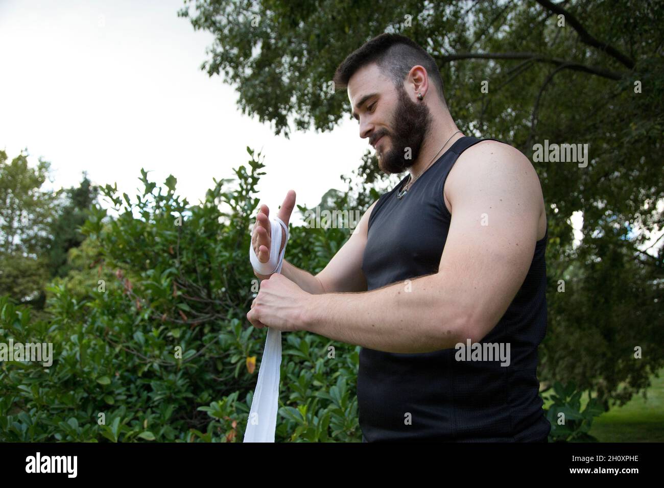 young bearded man caucasian boxer putting bandages on his hands to practice boxing Stock Photo