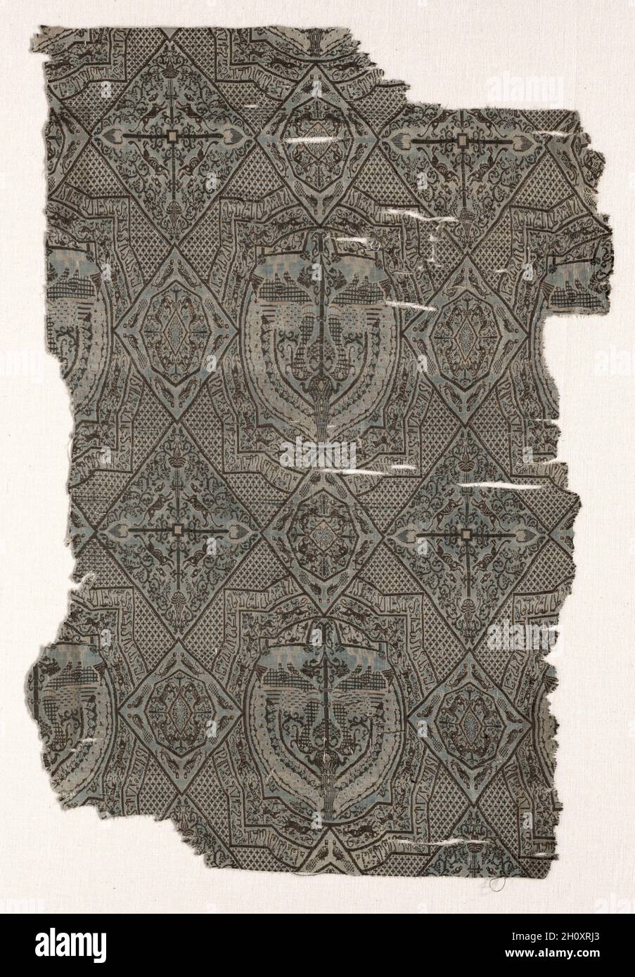 Fragments, before 1968. Iran or Iraq, in the style of the Seljuq period (1037–1194). Silk: lampas weave; average: 49 x 33 cm (19 5/16 x 13 in.).  Geometric medallions aligned on a diaper ground are enclosed in a grid of large and small lozenges. Medallions contain confronting peacocks flanking a Tree of Life. The double border has an inner frieze of running animals and an outer band of Kufic inscription. The larger diamonds contain four-directional palmette trees and two opposed pairs of rampant animals. The smaller diamonds have pairs of peacocks in each corner framing an octagon, which conta Stock Photo