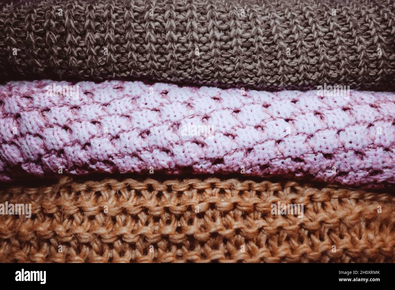 Three knitted cozy sweaters lying in a row. Autumn winter clothes