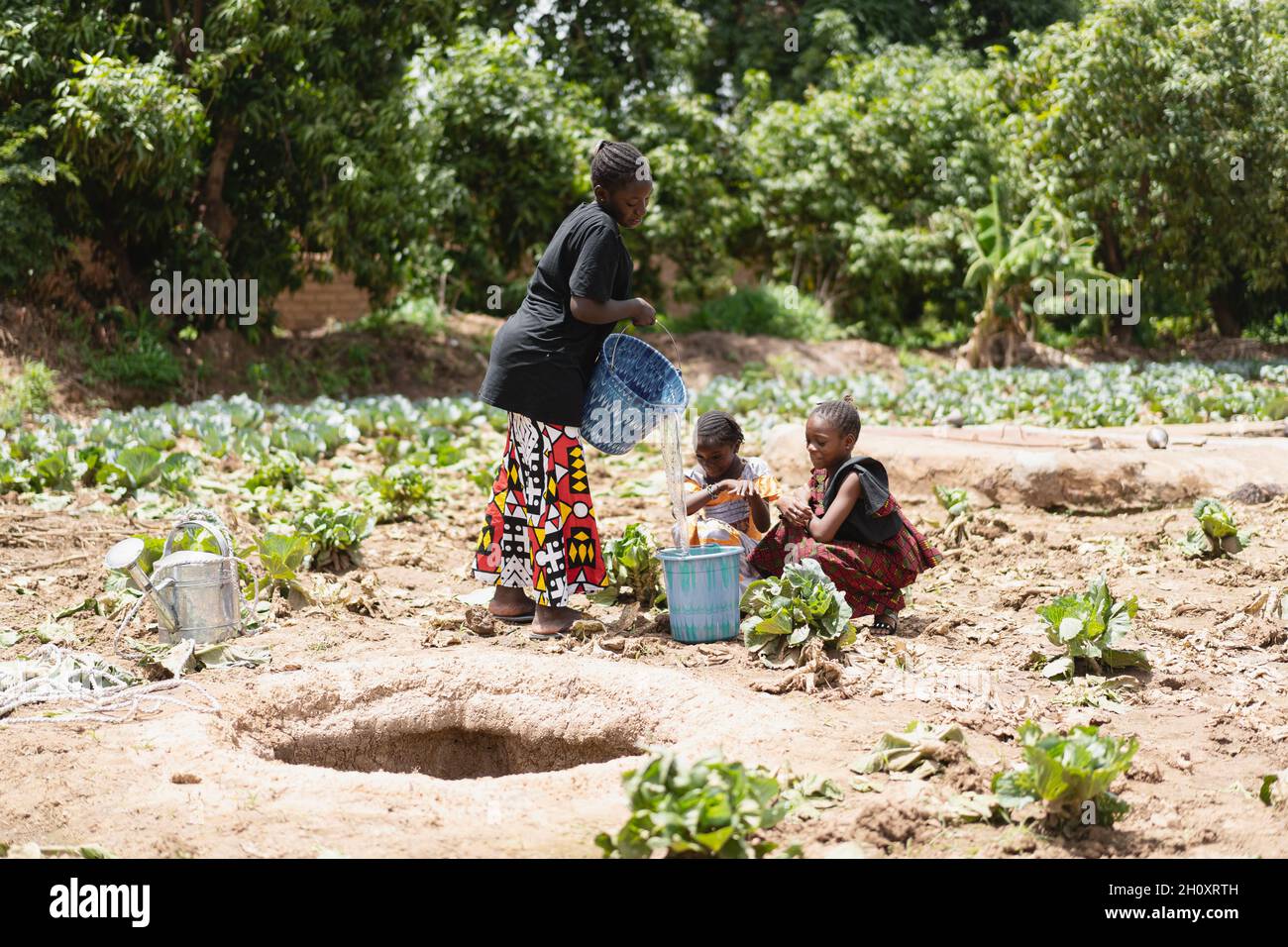 Group of black African girls at the village water hole filling water