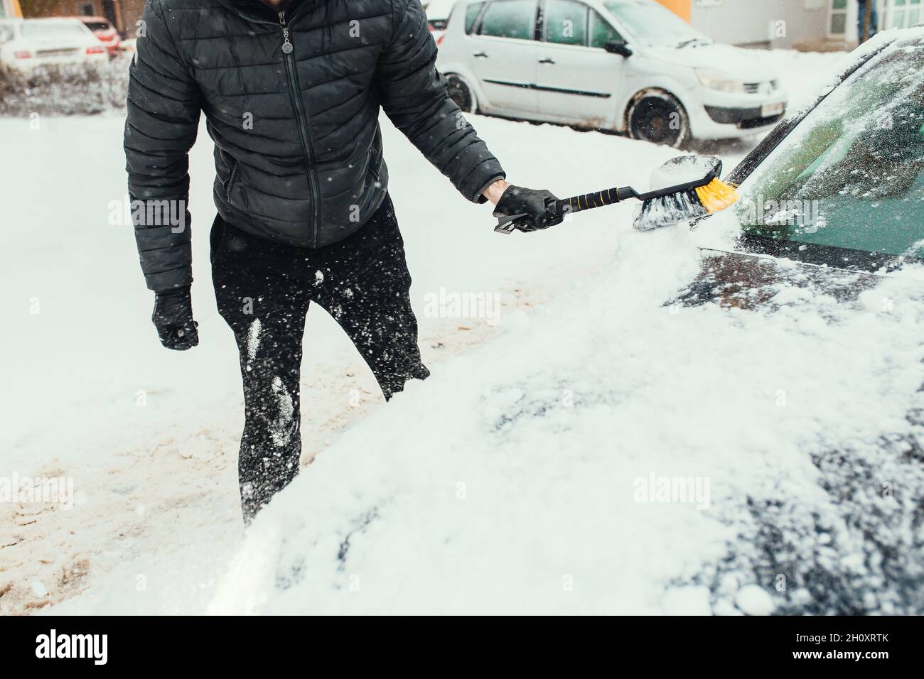 Clearing snow from glass and car body after heavy snowfall in winter