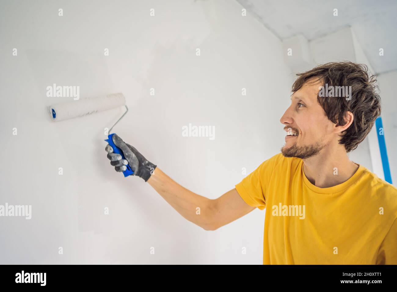 One male house painter worker painting and priming wall with painting