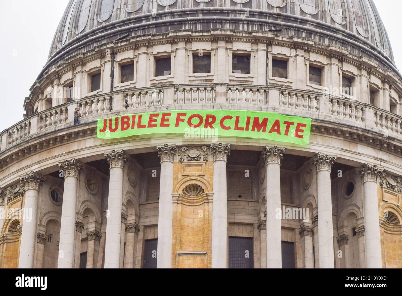 London, UK. 15th Oct, 2021. An activist hangs a banner on St Paul's Cathedral. Activists launched the Jubilee For Climate campaign, calling for the cancellation of all unfair debts, system change, transformation of the economy, and firm action on the climate and ecological crisis. Credit: Vuk Valcic/Alamy Live News Stock Photo