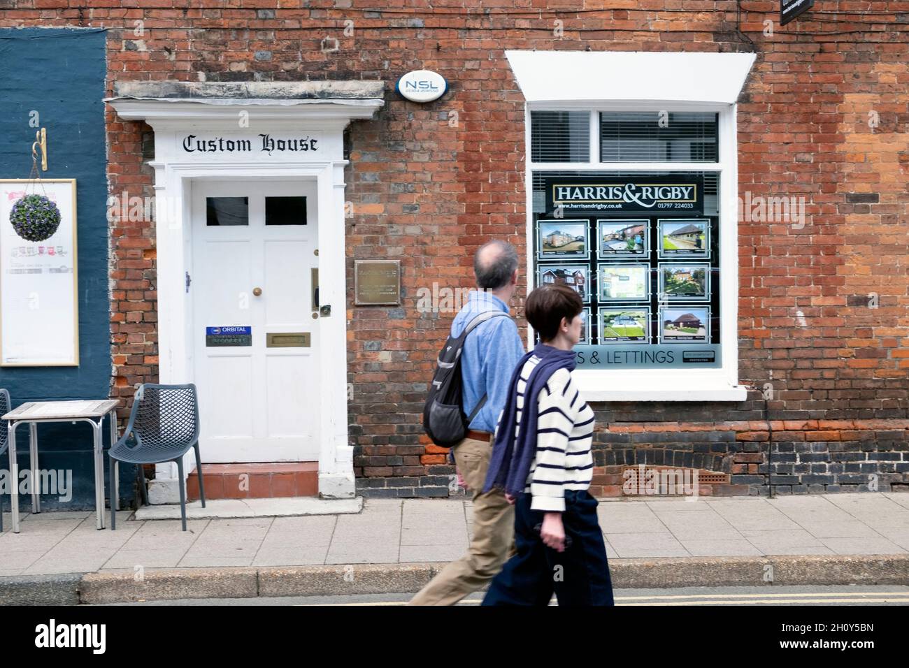 Couple people looking in Estate Agent window at houses for sale rent