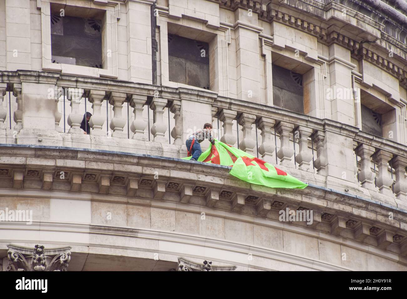 London, UK. 15th Oct, 2021. An activist who scaled St Paul's Cathedral removes the banner hanging from the cathedral. Activists launched the Jubilee For Climate campaign, calling for the cancellation of all unfair debts, system change, transformation of the economy, and firm action on the climate and ecological crisis. Credit: Vuk Valcic/Alamy Live News Stock Photo