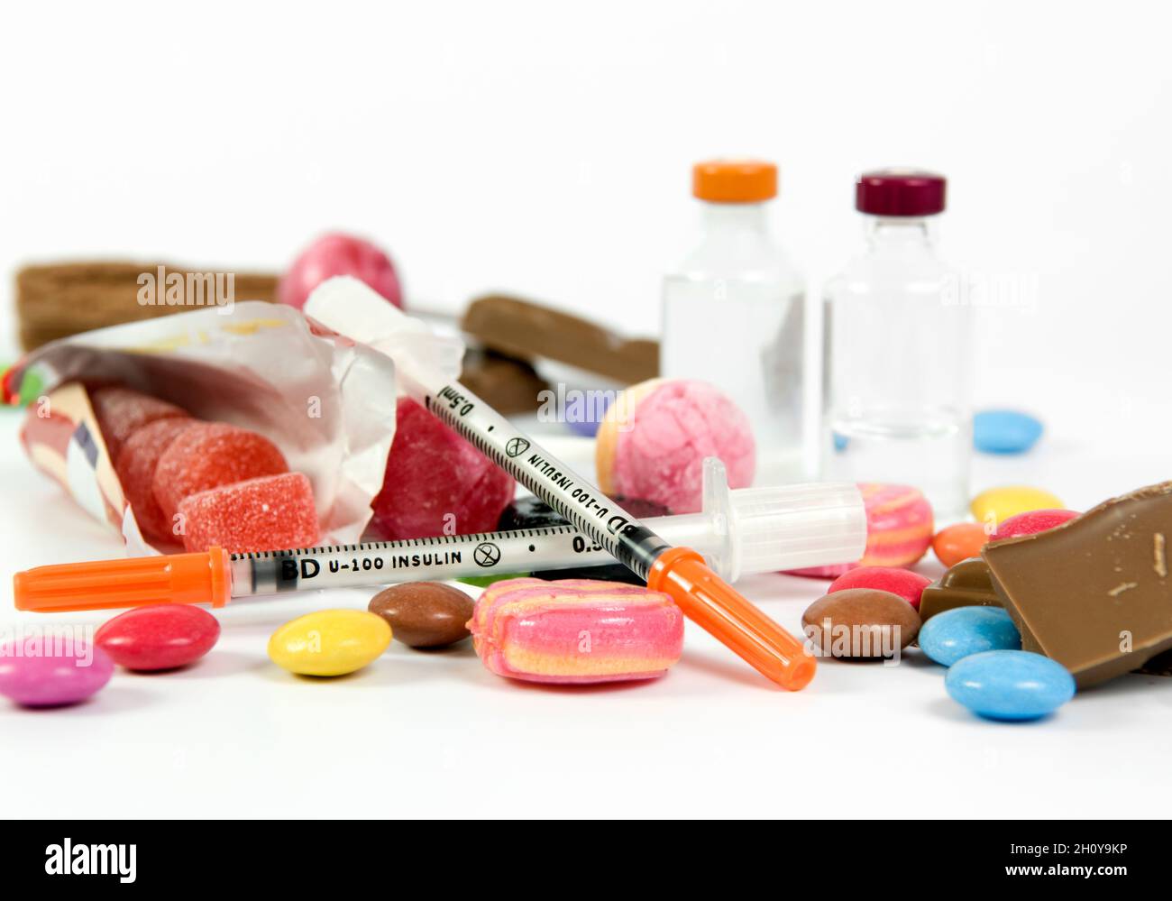 Long and short acting insulin vials with needles amongst sugary sweets