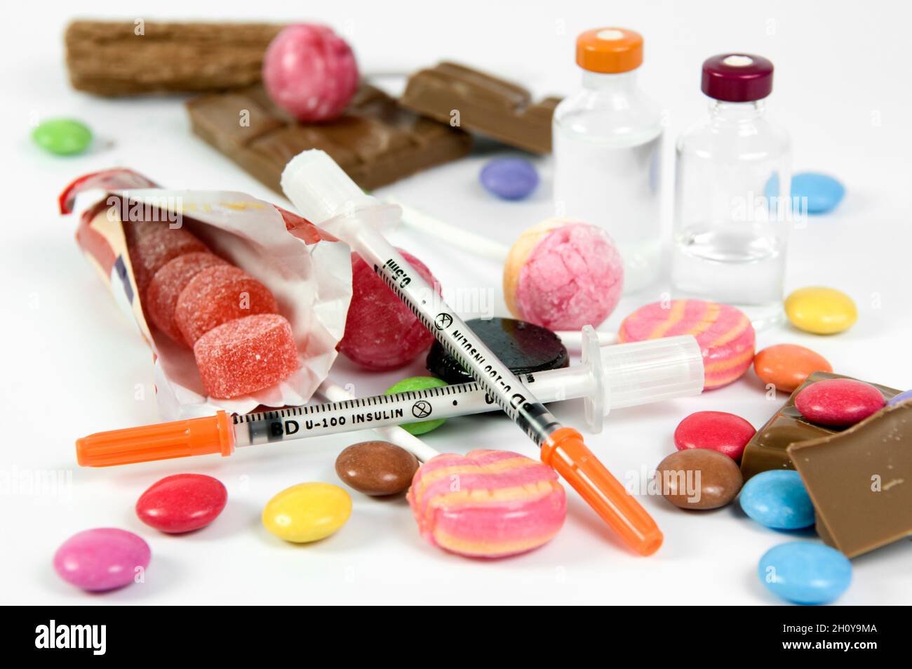 Long and short acting insulin vials with needles amongst sugary sweets
