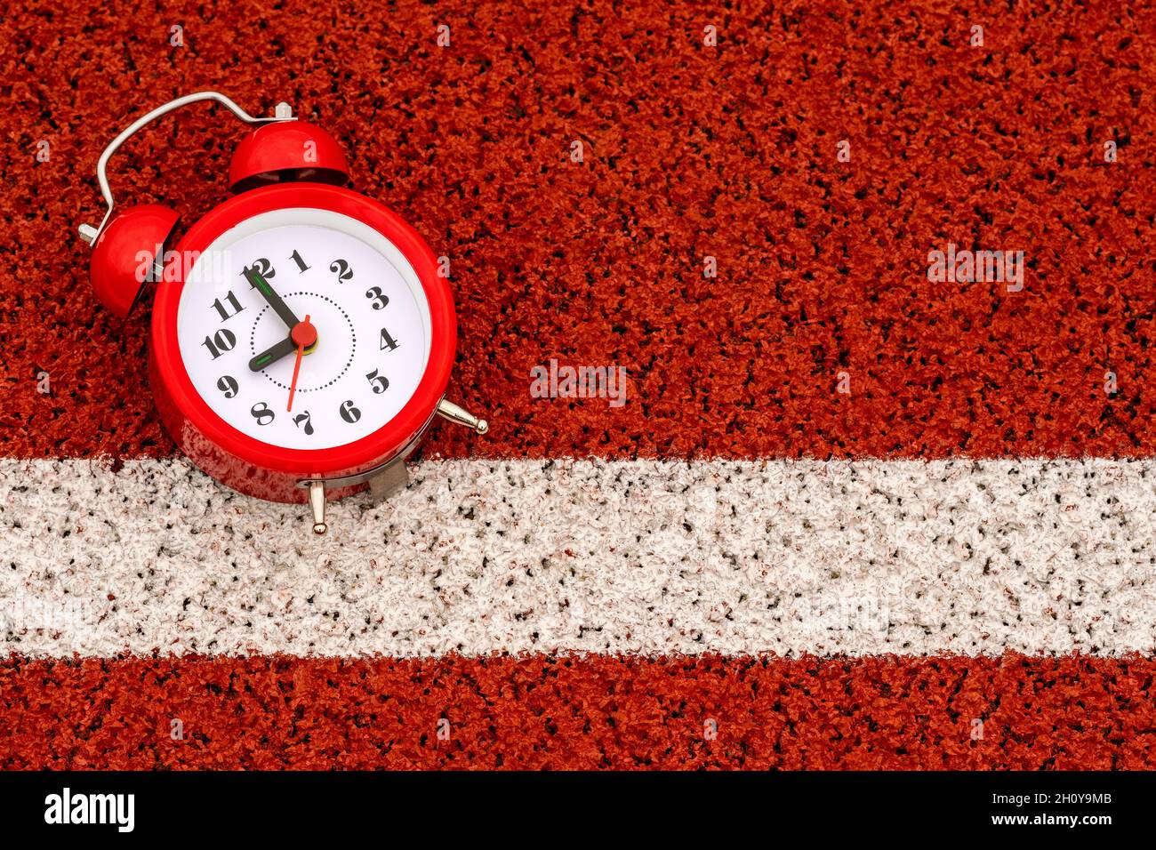 Alarm clock on the start line in sports stadium. Start for healthy life. Stock Photo