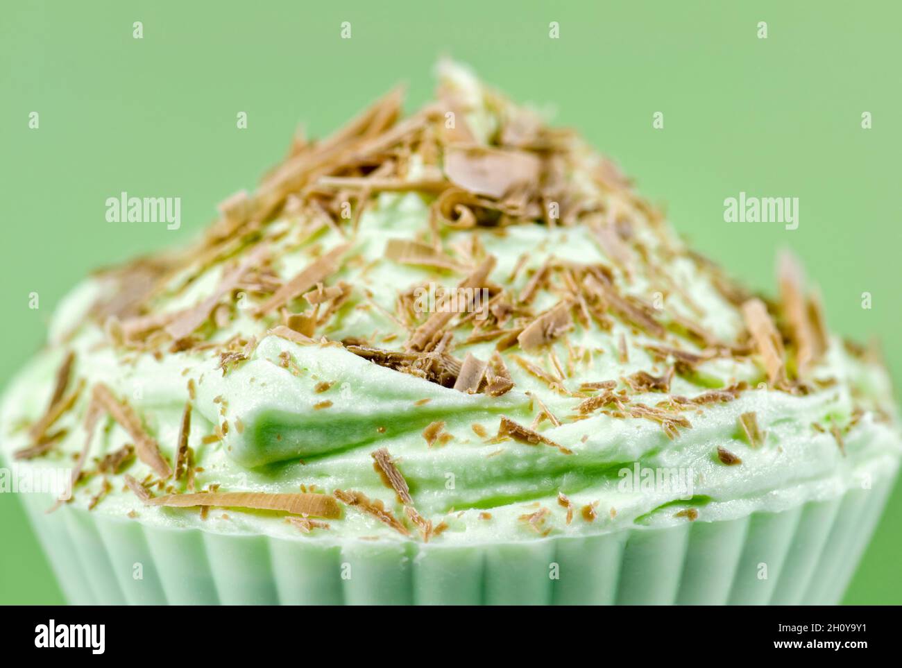 Pistachio cupcake with chocolate shavings and green icing against a pale green background Stock Photo