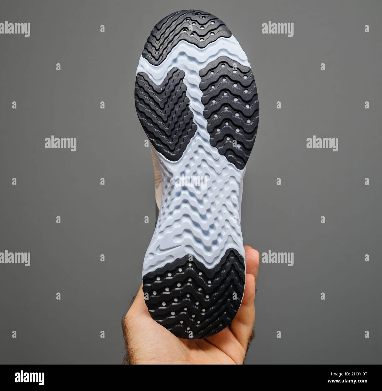 POV male hand holding isolated on gray background new Nike running shoe  with Swoosh logotype Stock Photo - Alamy