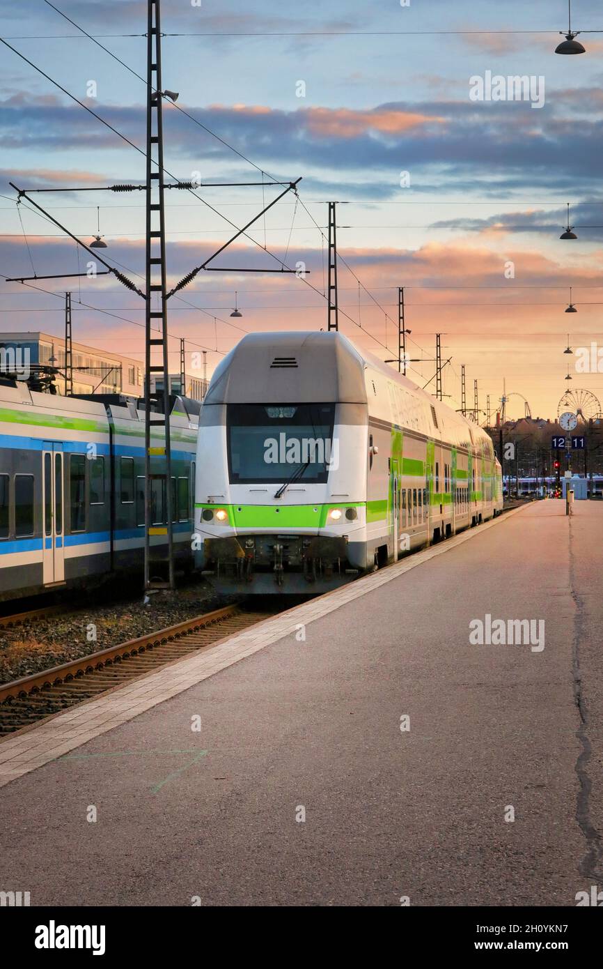 Modern electric 2 storey passenger train arrives at the platform of Helsinki railway station on a beautiful morning. Stock Photo
