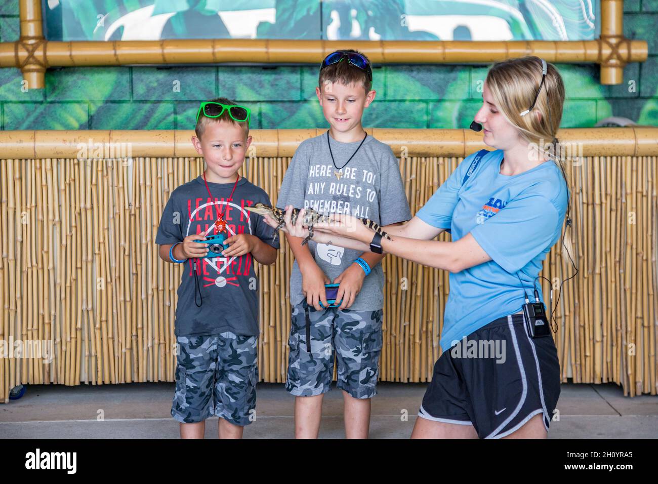Animal handler shows baby alligator to two boy guests at Ocean Adventures Marine Park in Gulfport, Mississippi Stock Photo