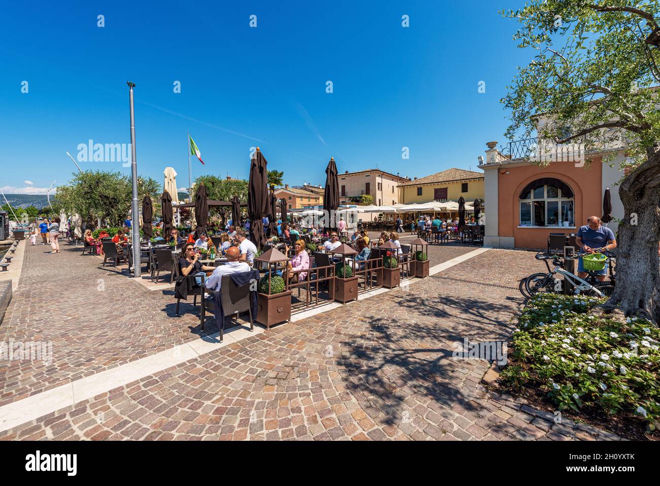 Outdoor restaurants with many people in the small village of Bardolino, Tourist resort on the coast of Lake Garda. Verona, Veneto, Italy, Europe. Stock Photo