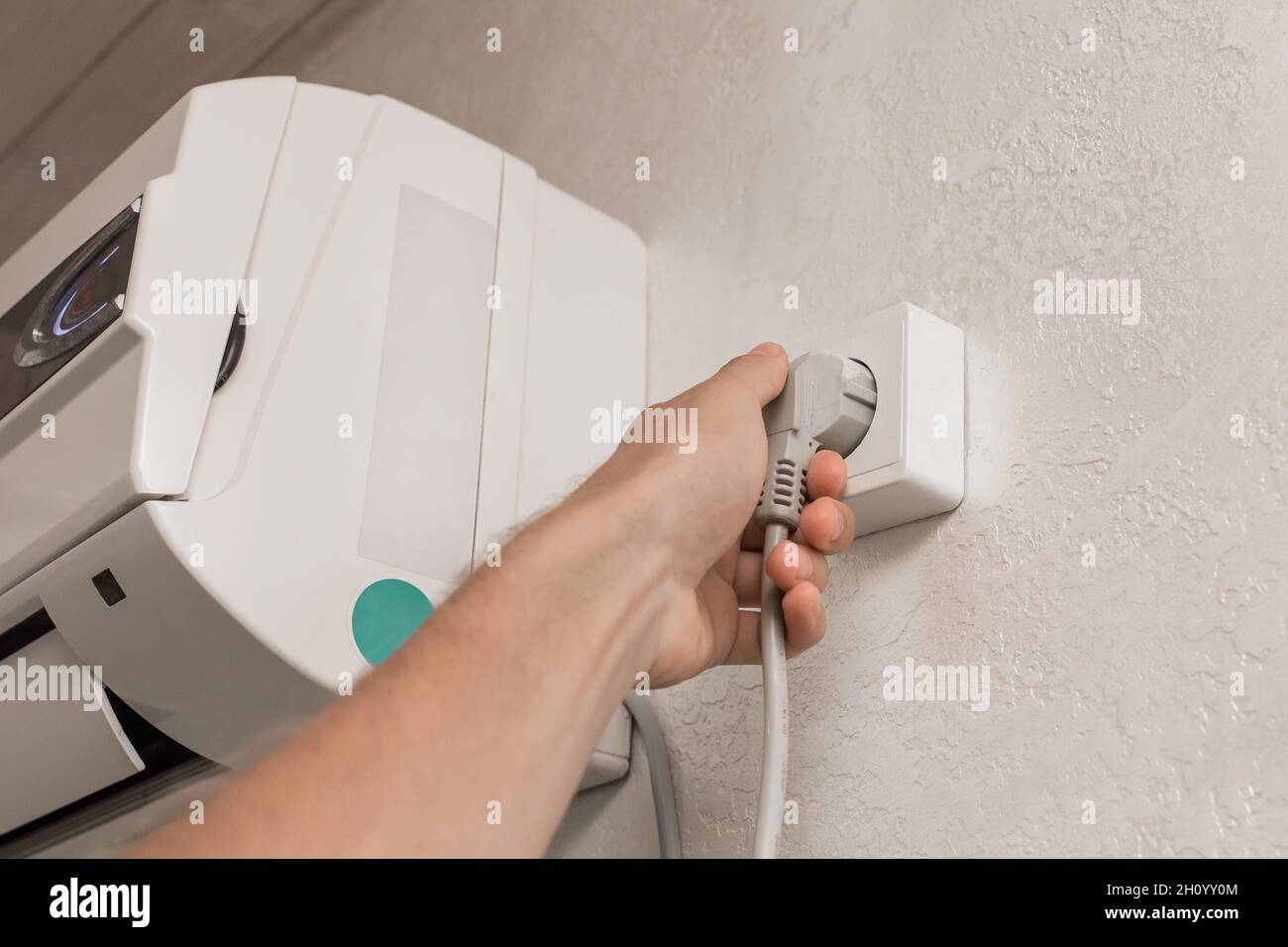 The hand disconnects or plugs the air conditioner power plug on the