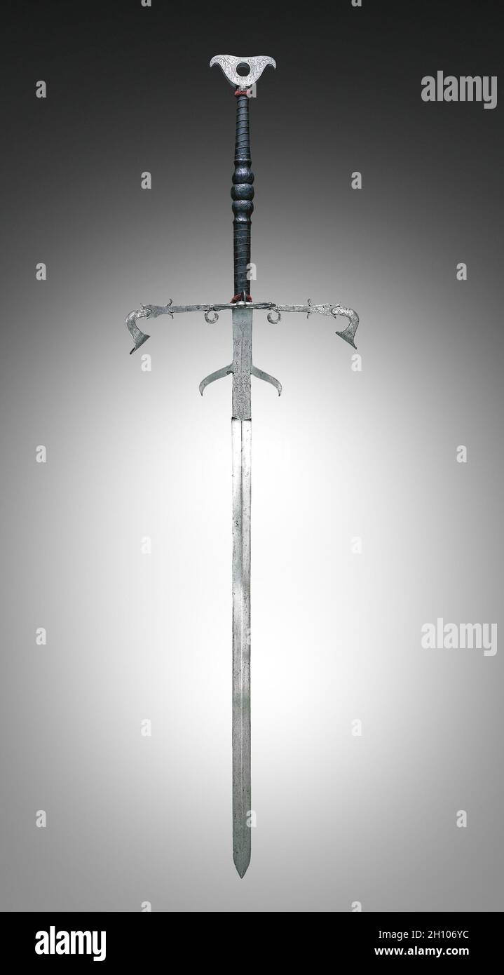 Two-Handed Sword of the State Guard of Julius of Brunswick-Lunüneburg, 1574. Germany, Brunswick, 16th century. Steel, leather and wire bound grip; overall: 186.1 cm (73 1/4 in.); blade: 132.1 cm (52 in.); quillions: 51.4 cm (20 1/4 in.); grip: 45.7 cm (18 in.); ricasso: 25.1 cm (9 7/8 in.).  This is one of a large series of swords distinguished by the fish-shaped crossbar on the hilt (quillon) and pierced, crutch-shaped pommels. Each sword in this series is also dated and numbered. The crowned monogram of Duke Julius, the year 1574, and the number of this particular sword (N 59) are etched on Stock Photo