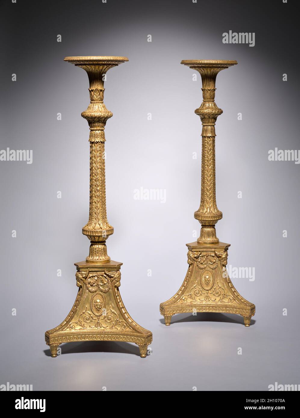 Pair of Candle Stands (torchères), c. 1773. Thomas Chippendale (British, 1718–1779). Gilt-wood, gesso; each: 154 x 56 x 51 cm (60 5/8 x 22 1/16 x 20 1/16 in.).  This pair of gilded candle stands was made by Thomas Chippendale, the most renowned cabinetmaker in eighteenth-century London, for the grand drawing room of Brocket Hall, a large country house in Hertfordshire, England. With finely carved acanthus leaves, swags, fluting, and oval masks depicting the Roman goddess Diana, these candle stands exhibit Chippendale’s masterful understanding of neoclassical proportion, scale, and ornament. Hi Stock Photo