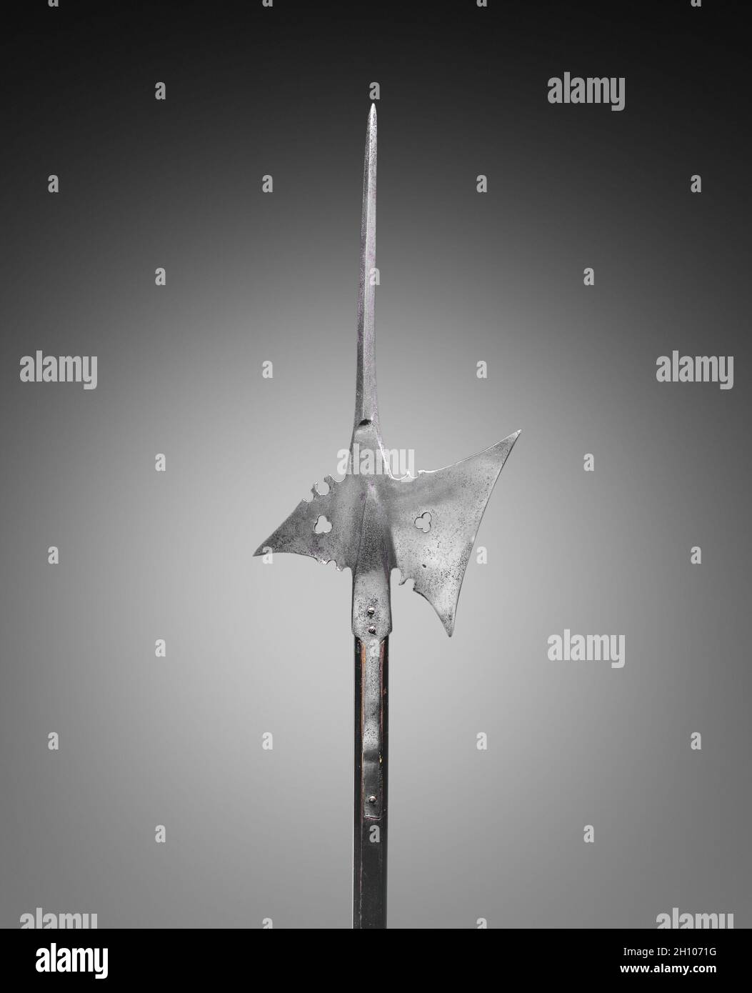 Halberd, c. 1550. Germany, 16th century. Steel, with pierced trefoils; wood haft (rectangular with planed corners); overall: 200.7 cm (79 in.); blade: 25.4 cm (10 in.).  The most effecient weapons used by the infantry (foot soldiers) during the 15th and 16th centuries were pole arms (or staff weapons). The halberd, like the examples shown here, was a weapon of great versatility. The word halberd comes from the German words Halm (a staff) and Barte (an axe). The halberd is, in fact, an axe mounted on a long pole with a very specialized shape and function: the axe blade was used for hacking, the Stock Photo