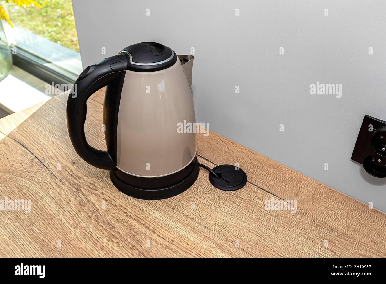 https://c8.alamy.com/comp/2H10937/an-electric-kettle-standing-on-the-countertop-on-the-kitchen-cabinets-visible-hole-in-the-table-top-through-which-the-electric-cable-goes-2H10937.jpg