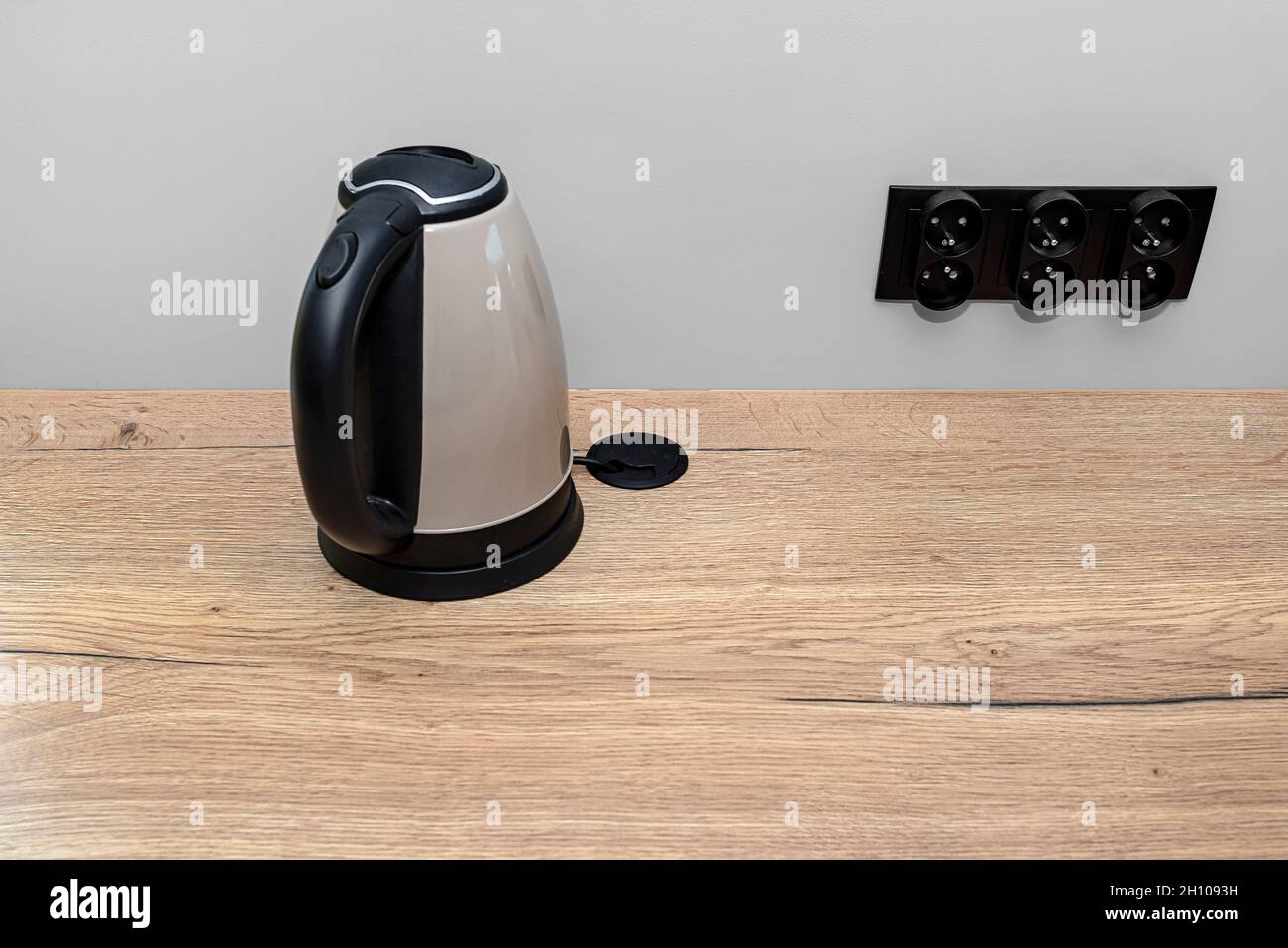 https://c8.alamy.com/comp/2H1093H/an-electric-kettle-standing-on-the-countertop-on-the-kitchen-cabinets-visible-hole-in-the-table-top-through-which-the-electric-cable-goes-2H1093H.jpg