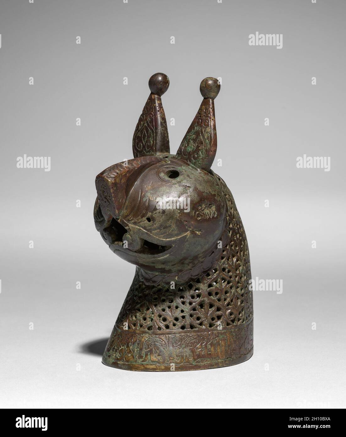 Head for a Feline Incense Burner, 1150–1200. Iran, Khurasan, Seljuq period of Iran (1037–1194). Copper alloy, cast, engraved, chased, and pierced; overall: 36 cm (14 3/16 in.).  In Iran during the 1000s and 1100s, vessels in the shape of animals gained popularity, especially as incense burners. Felines were favored in Persian art and this piece may represent a caracal, a type of lynx. The head of the creature was cast separately and is removable to fill its body with hot coals and incense. Qur’anic verses on the neck and spine remind worshippers to set work aside, attend prayer, and then dispe Stock Photo