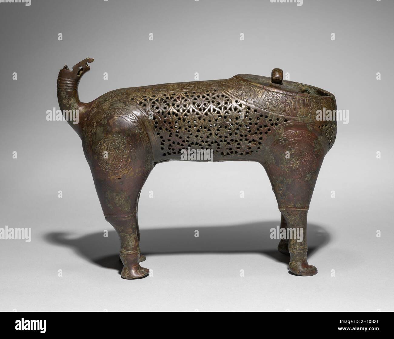 Feline Incense Burner, 1150–1200. Iran, Khurasan, Seljuq period of Iran (1037–1194). Copper alloy, cast, engraved, chased, and pierced; overall: 35.5 x 11 cm (14 x 4 5/16 in.); head: 17.8 x 9.5 x 12.5 cm (7 x 3 3/4 x 4 15/16 in.).  In Iran during the 1000s and 1100s, vessels in the shape of animals gained popularity, especially as incense burners. Felines were favored in Persian art and this piece may represent a caracal, a type of lynx. The head of the creature was cast separately and is removable to fill its body with hot coals and incense. Qur’anic verses on the neck and spine remind worshi Stock Photo