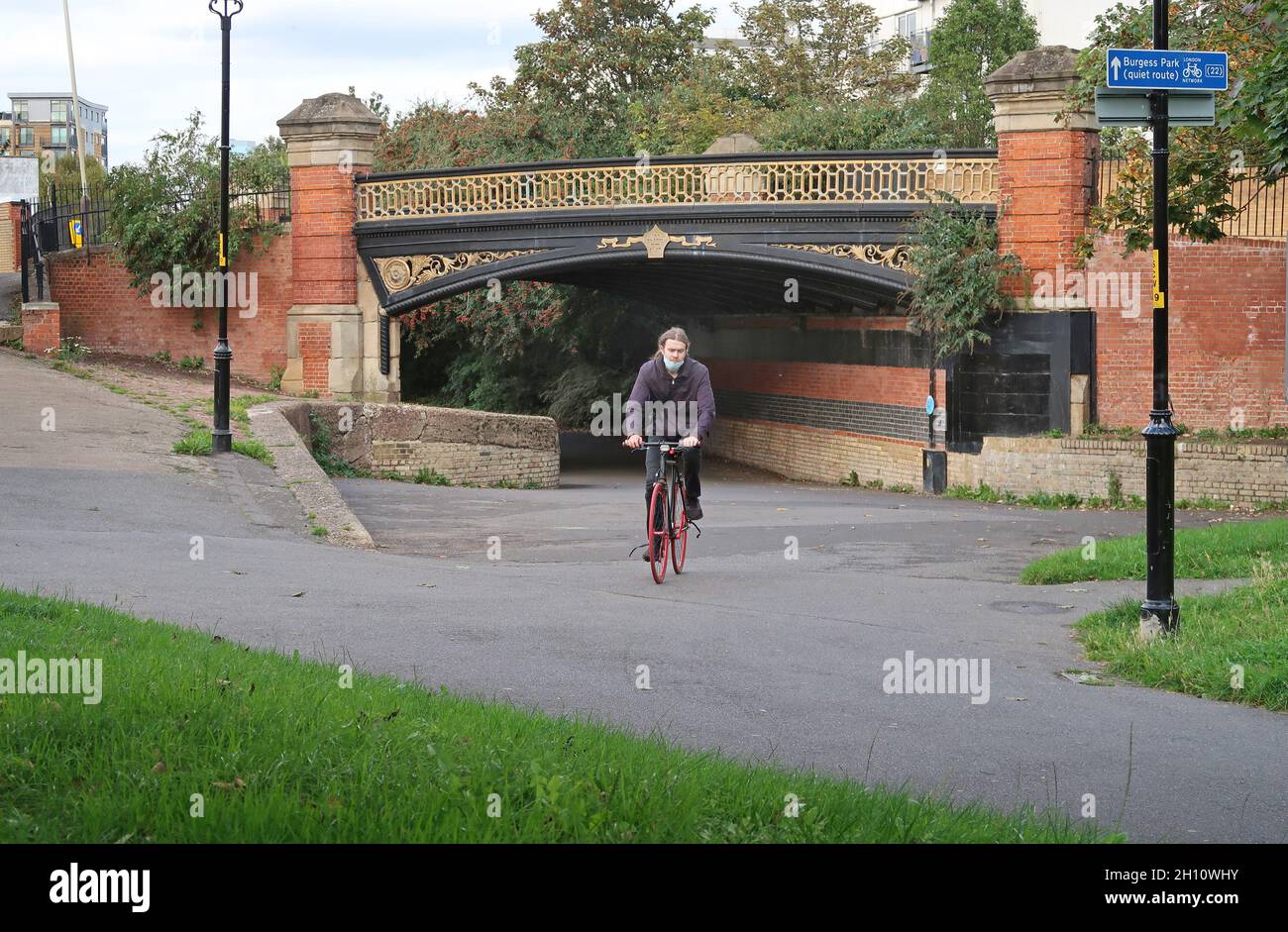 Peckham, south London, UK. A cyclist passes under a Victorian bridge on the old Surrey Canal route which is now a landscaped path and cycle route Stock Photo