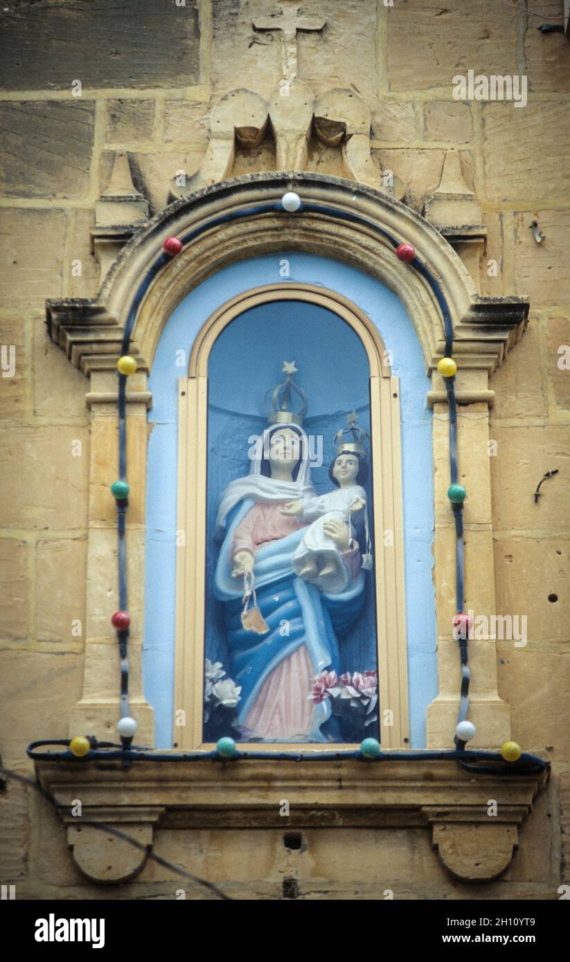 Marienstatue an einem Haus in der Altstadt von Gharb auf der Insel Gozo - A statue of the Mother of God with Baby Jesus at Gharb old town on Gozo island. Stock Photo