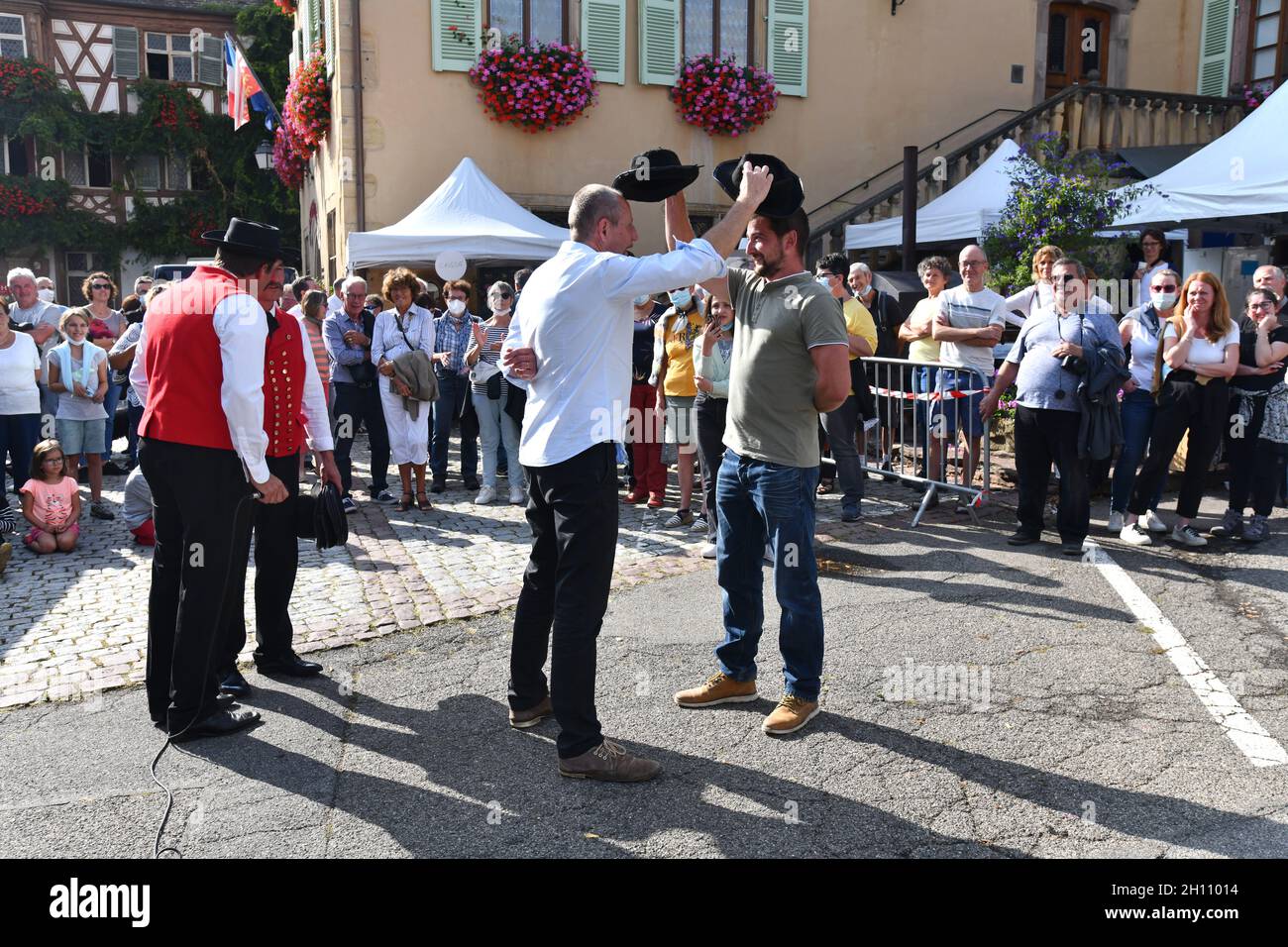 Men playing musical hats with traditional Alsace folk dancing group in the village of Turkheim during the Alsace grape harvest 2021 Stock Photo