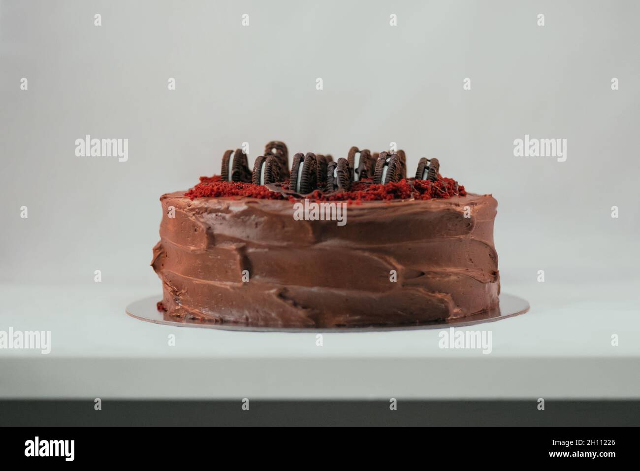 Delicious rich dark cake with Oreo on top on white background. Beautiful  tasty sweet dessert with multiple layers decorated with cookies Stock Photo  - Alamy