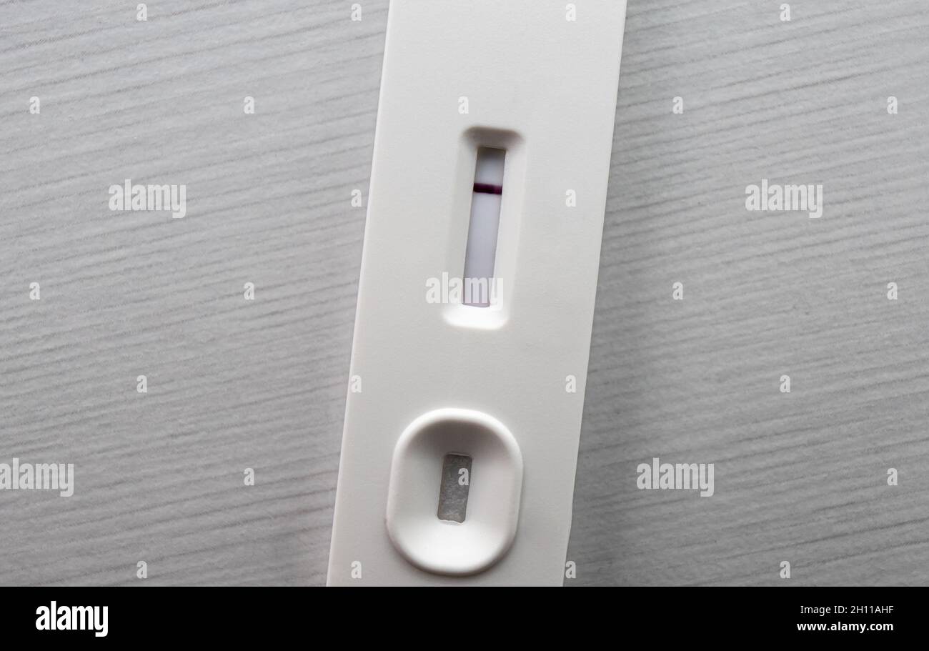 Testing with white generic home use slide test. Negative result with one red stripe. Covid-19 or pregnancy test concept. Copy space and room for text. Stock Photo