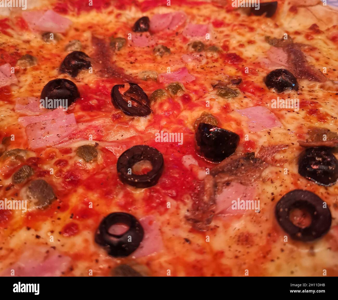Full frame image of pizza with black olives and tomato Stock Photo