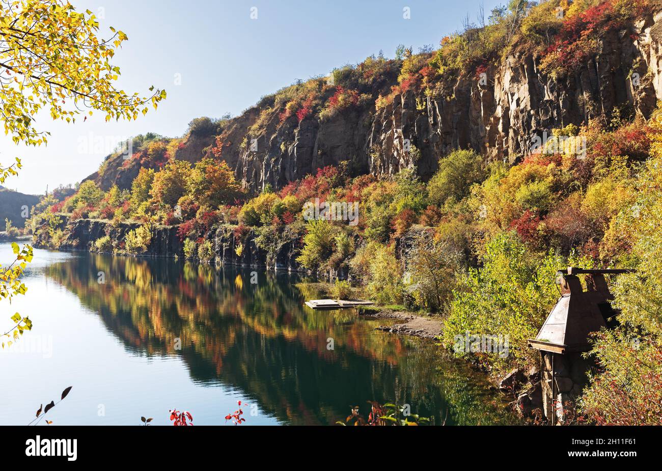 Golden autumn with colourful trees in old flooded quarry. Rocks, lake ...