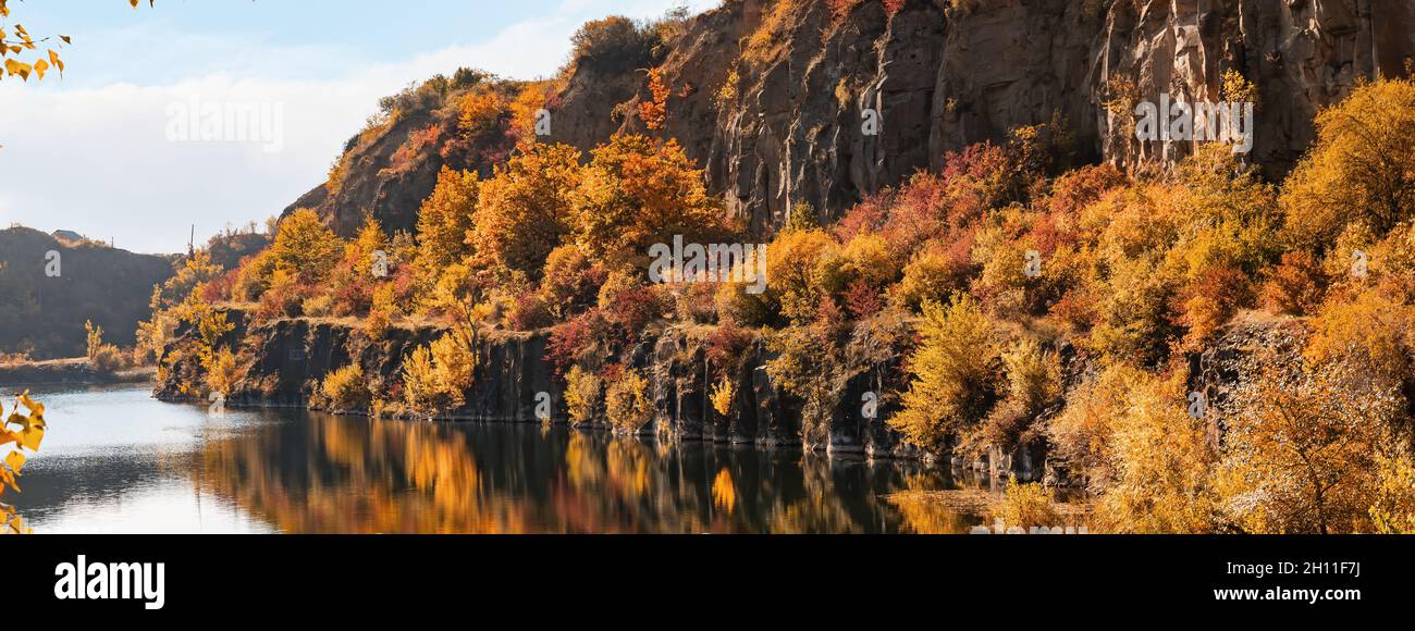 Golden autumn with colourful trees in old flooded quarry. Rocks, lake ...