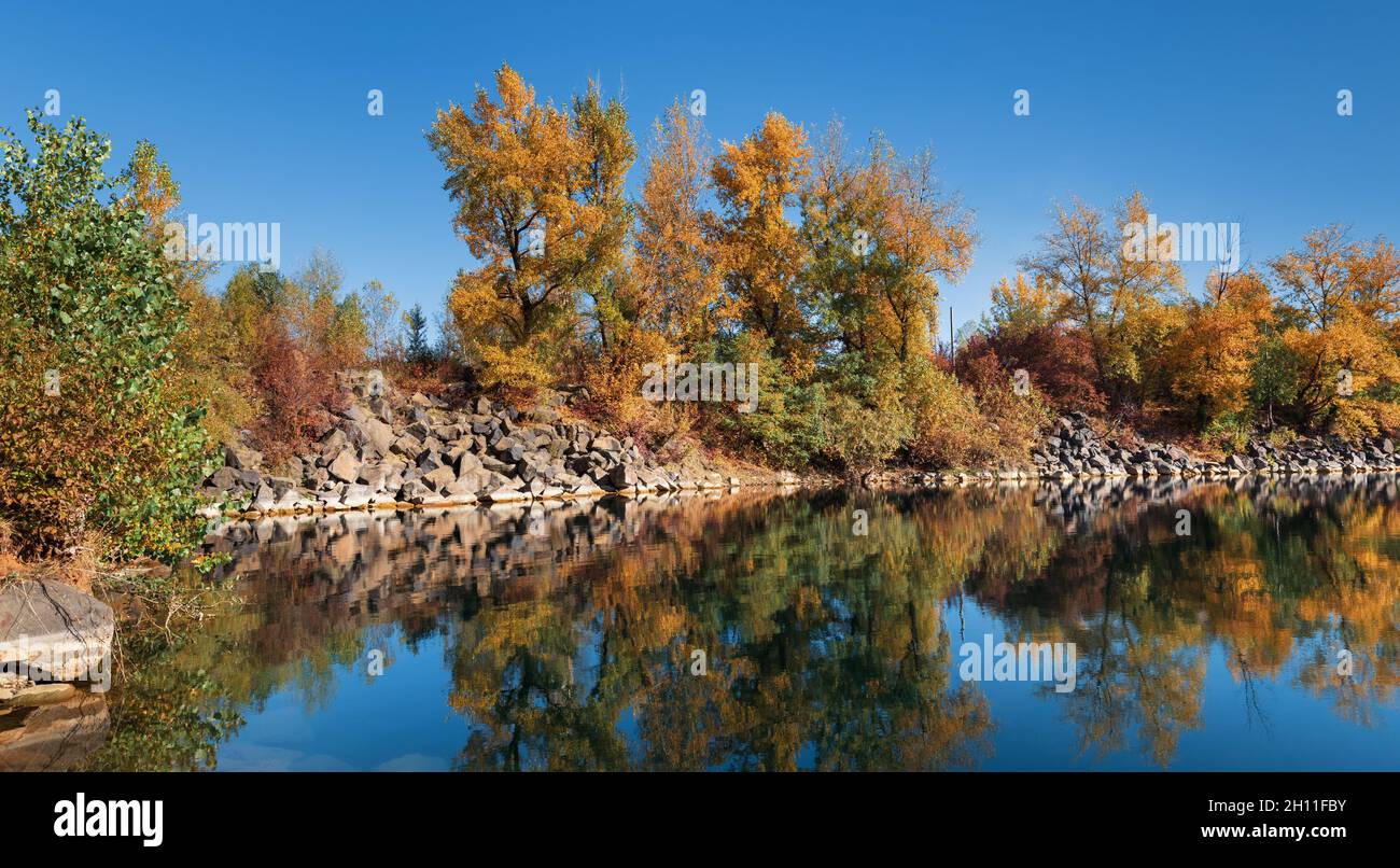 Golden autumn with colourful trees in old flooded quarry. Rocks, lake ...