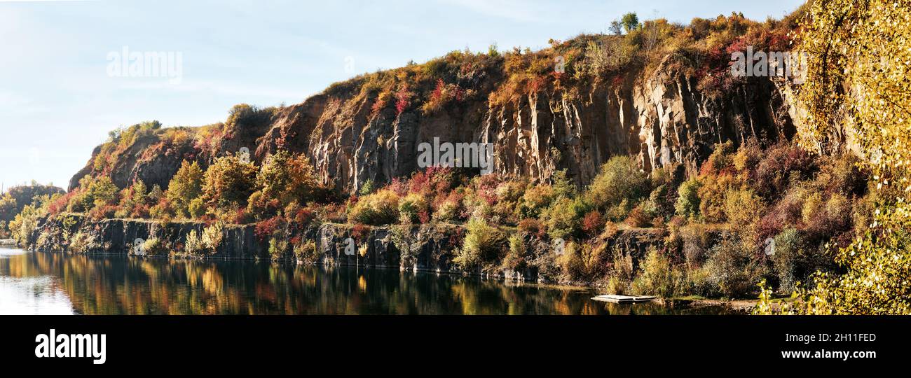 Golden autumn with colourful trees in old flooded quarry. Rocks, lake ...