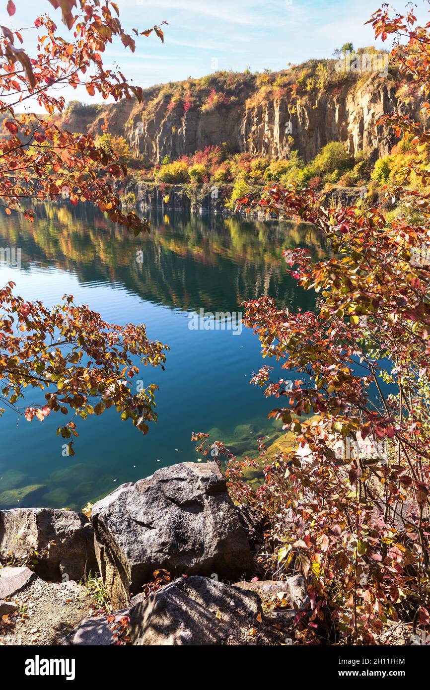 Golden autumn with colourful trees in old flooded quarry. Rocks, lake ...