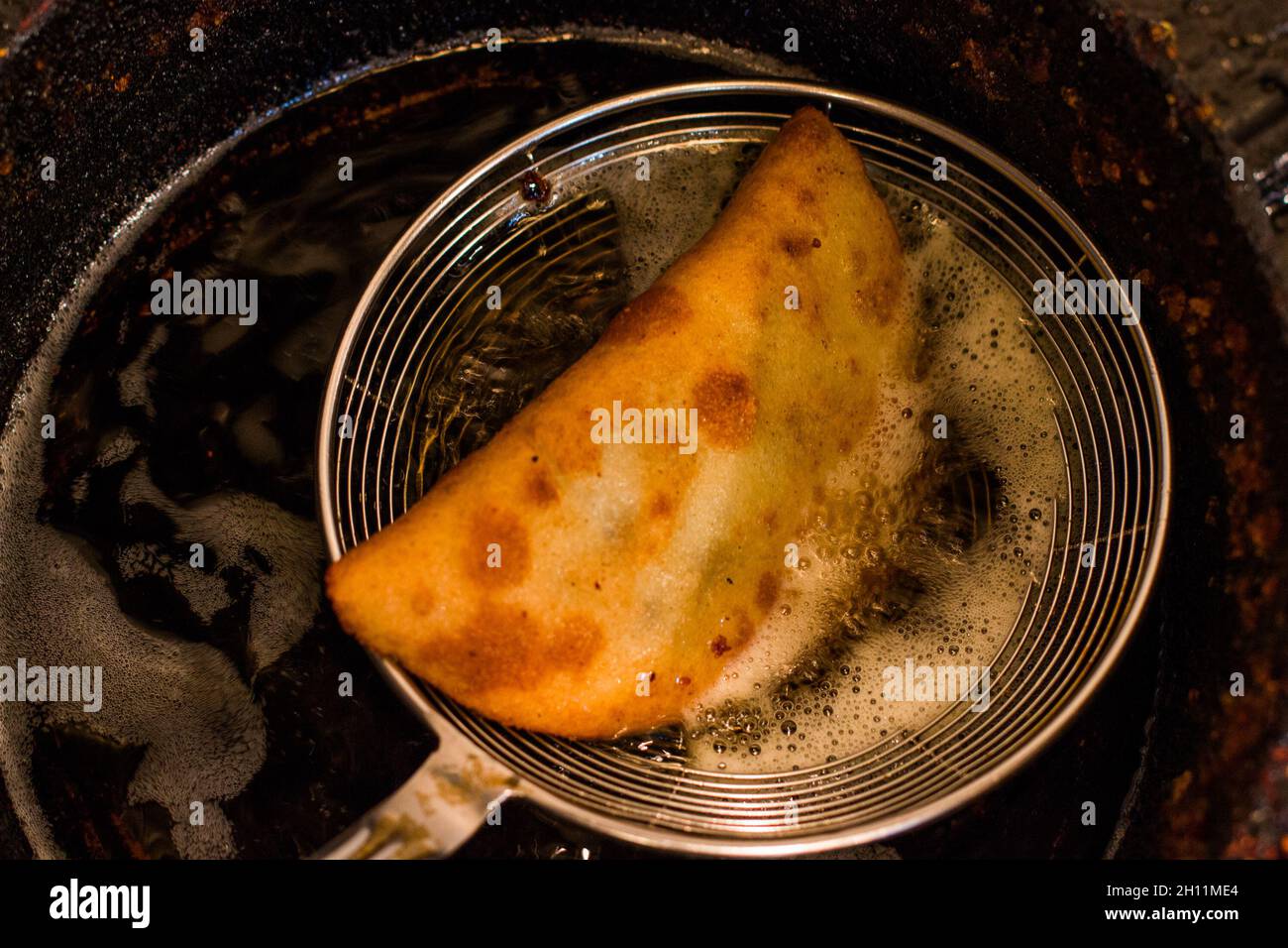 Closeup of newly cooked empanada scooped out from a pot and drained Stock Photo