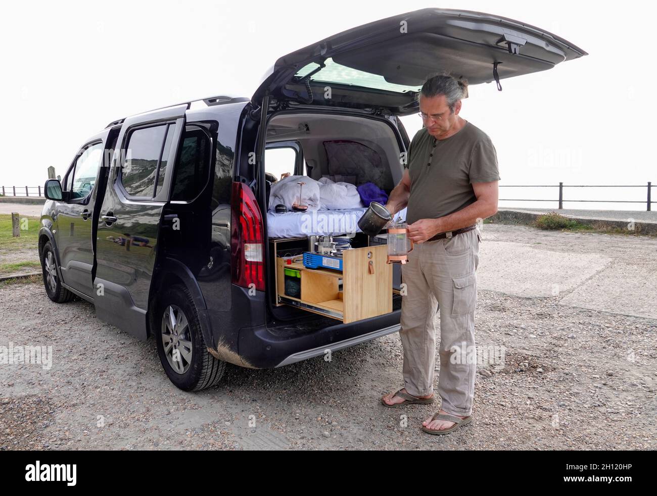 Man making coffee  for breakfast at the rear of his mini camper van Stock Photo
