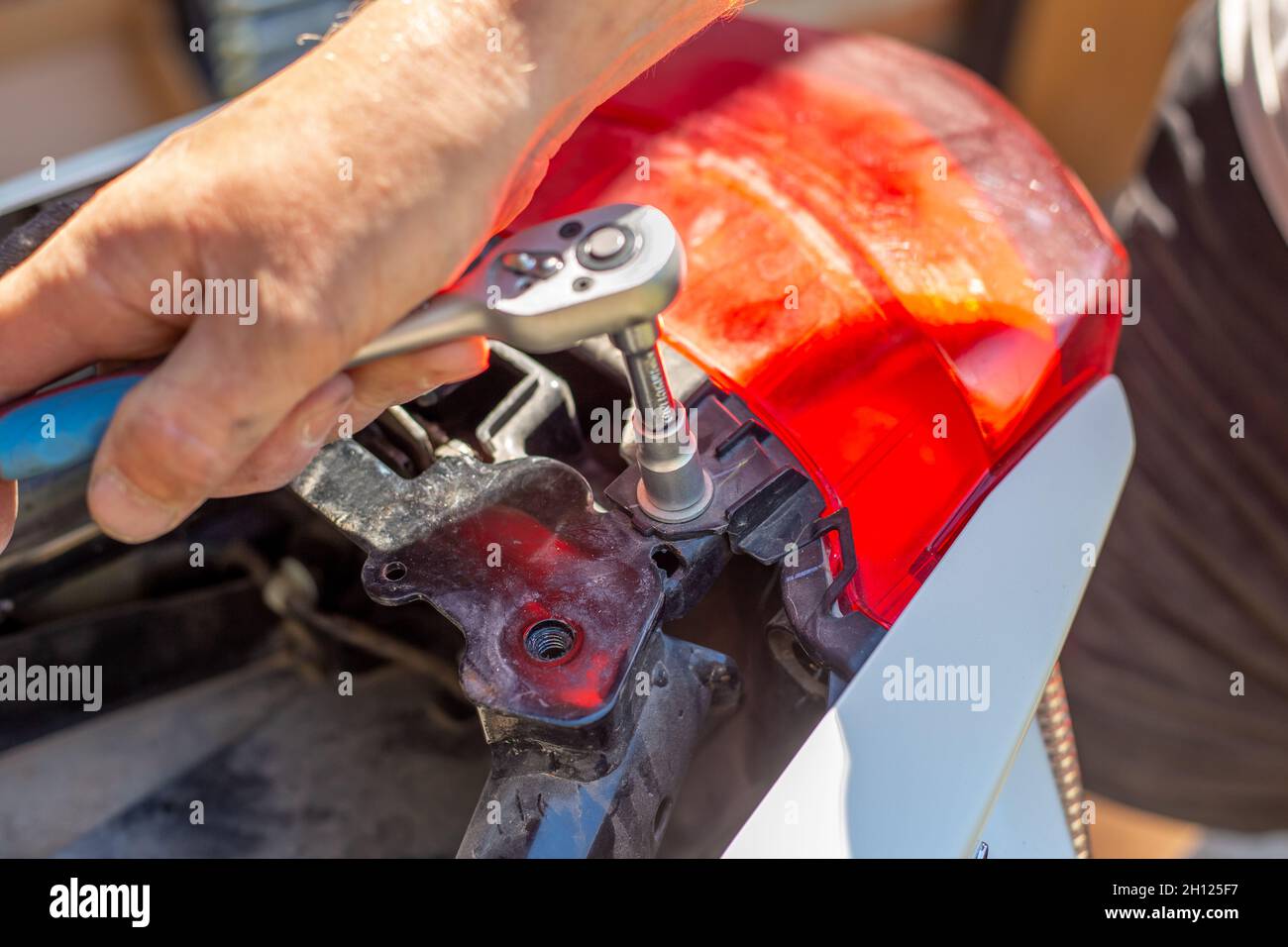 Motorcycle repair and maintenance. The man unscrews the fasteners with