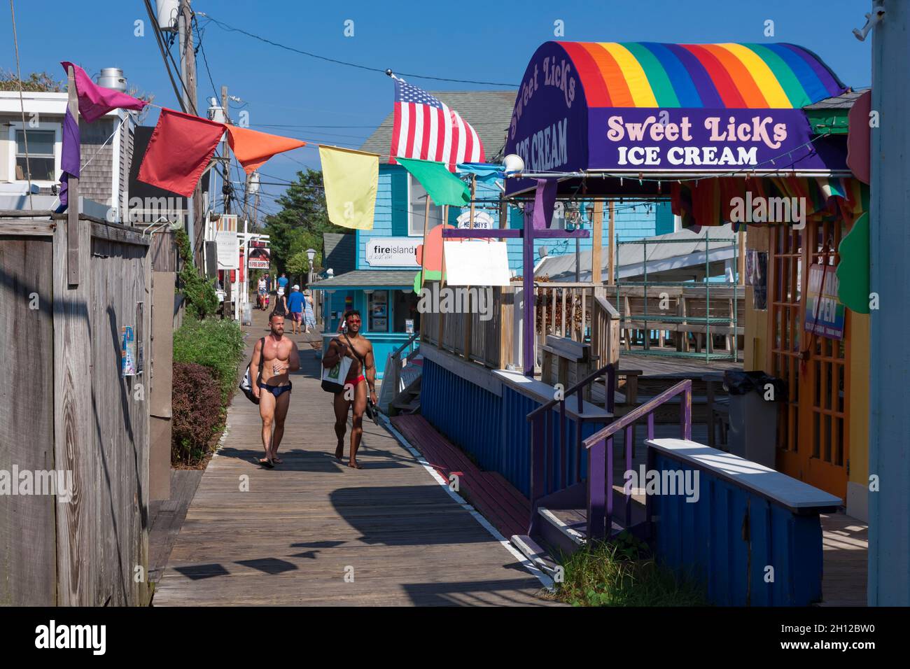 Shirtless men pass restaurants and shops in the center of town in Cherry Grove,  on Fire Island, Suffolk County, New York, USA. Stock Photo