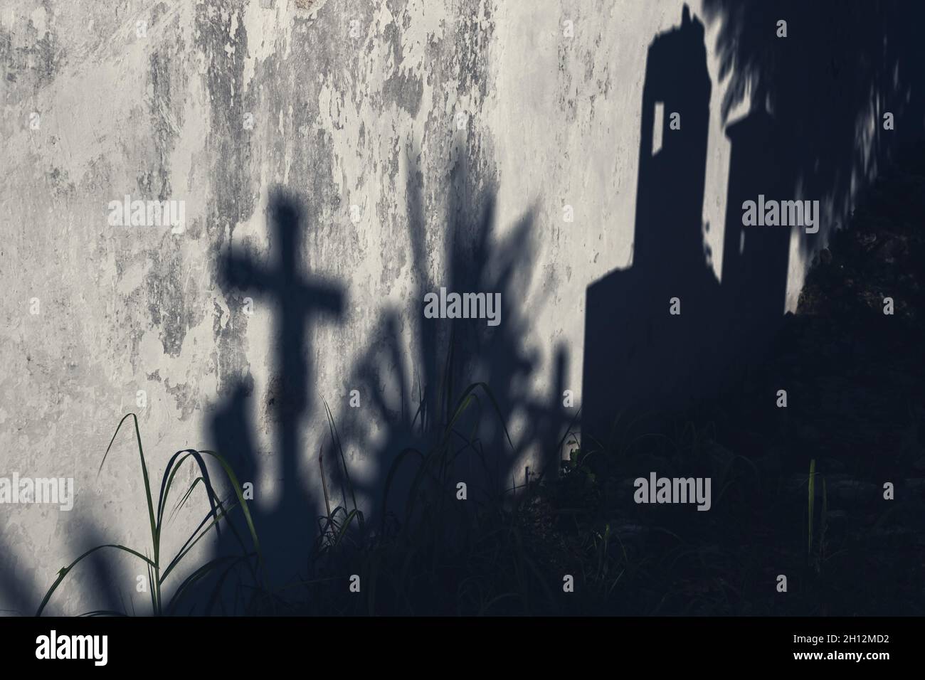 Scary abstract moonlight shadows of grave cross and tombstones on abandoned wall on a cementery ...