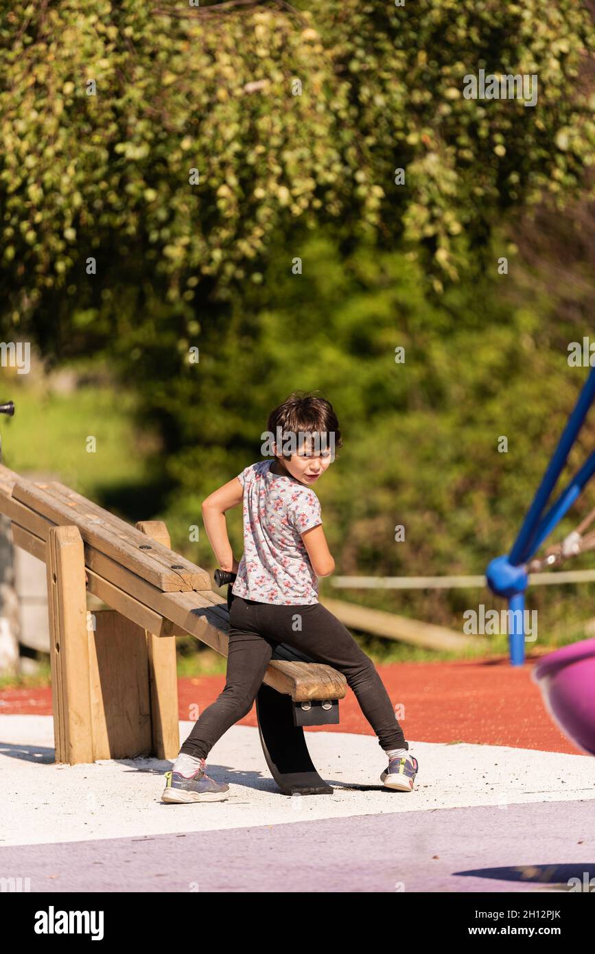 a little girl plays on the seesaw in the children's playground. Stock Photo