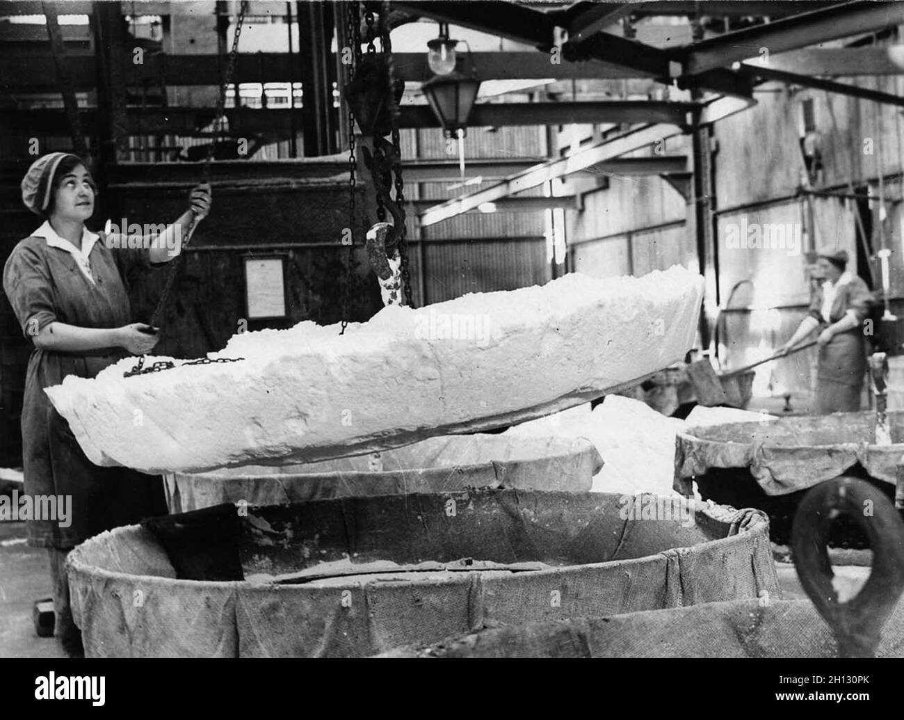 A woman worker hauls a cake of nitrate ammonia out of a dryer in a chemical plant. Stock Photo