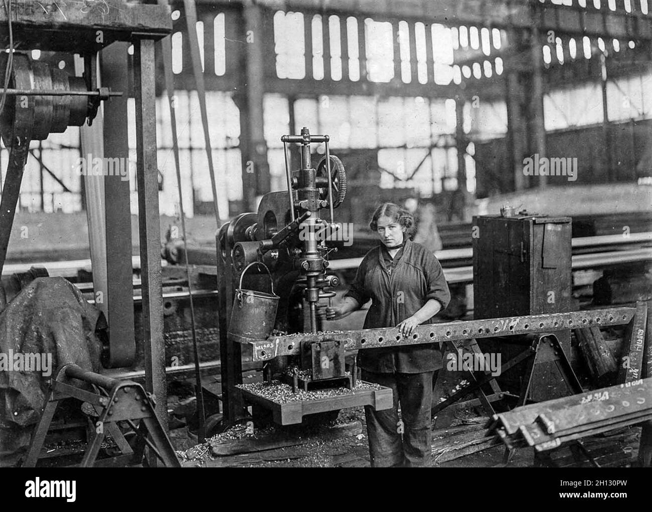 A worker drills holes for the ribs of airship sheds in a factory during WW1. Stock Photo