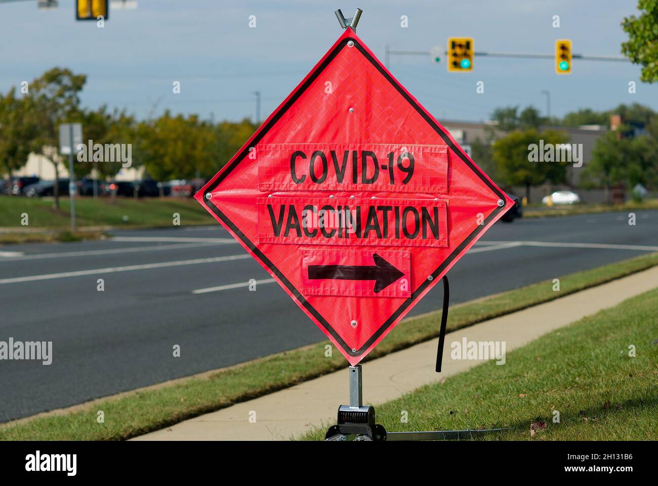Woodbridge, Virginia, USA - October 15, 2021: A bright orange 'construction' sign shows drivers the entrance to a public COVID-19 vaccination site. Stock Photo